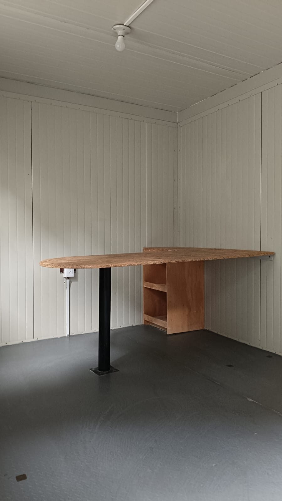 Interior de oficina móvil 8x24 con escritorio, multicontacto, luz y archivero