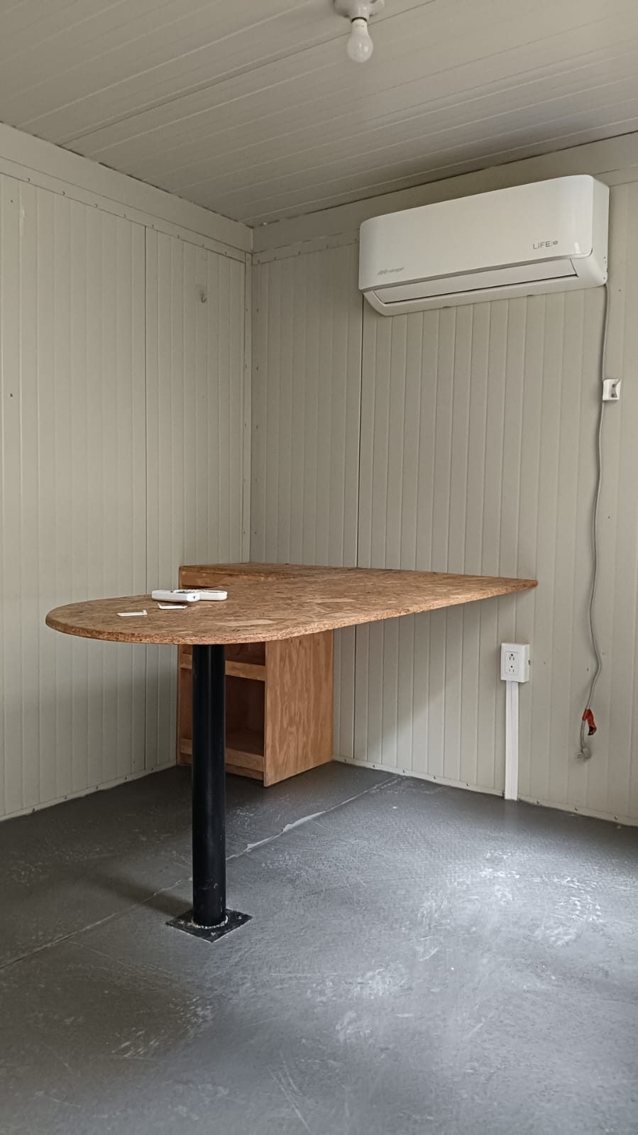 Interior de oficina móvil 8x24 con escritorio de esquina, minisplit, luz y multicontacto
