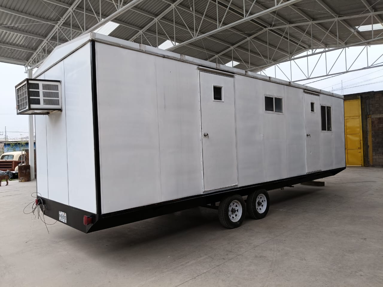 Oficina móvil JORAM 8x32, se aprecia el aire acondicionado, dos puertas, dos ventanas, y su doble eje.